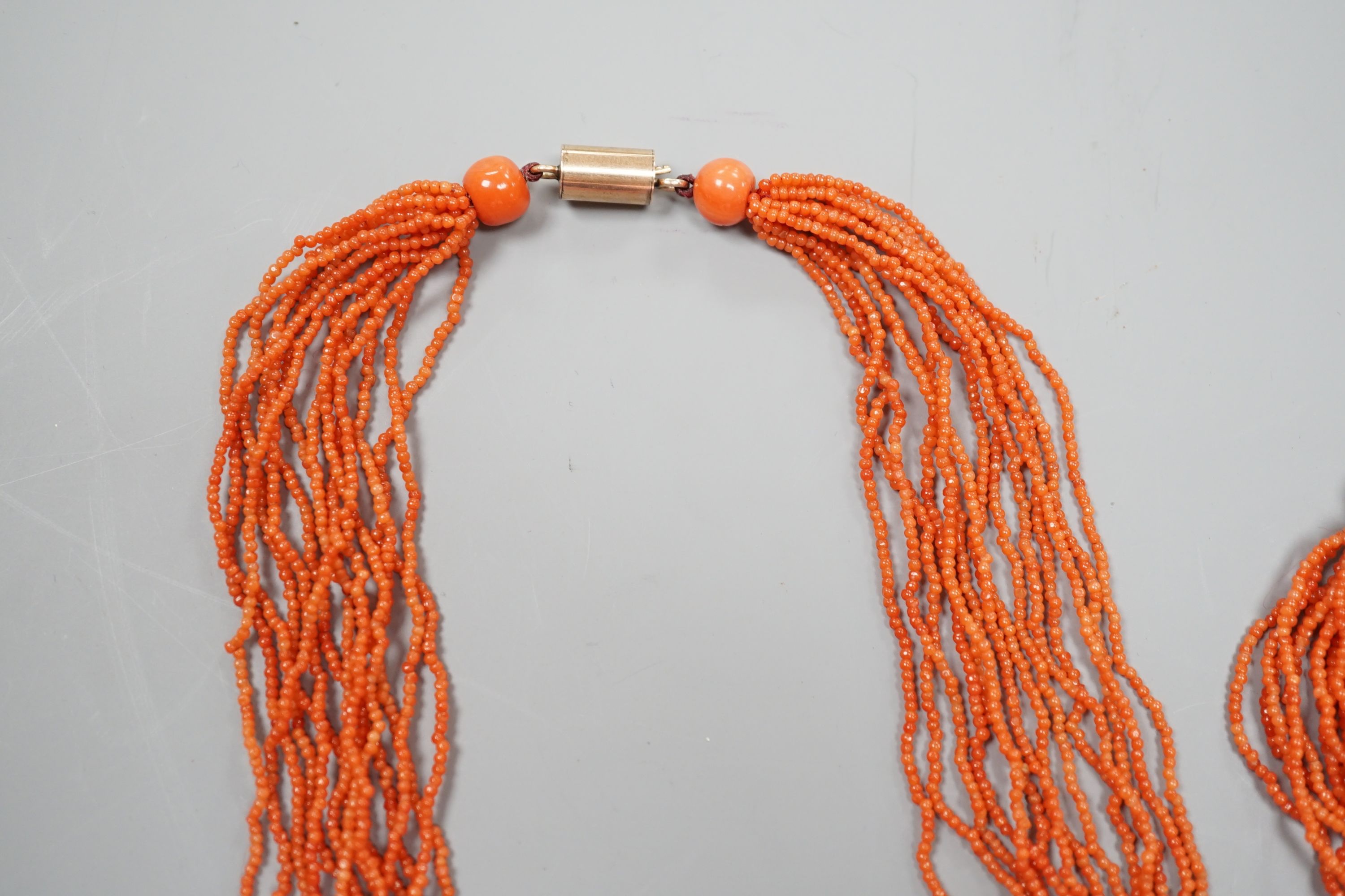 A multi strand coral bead necklace, 39cm and matching bracelet, 15.5cm, both with yellow metal barrel shaped clasps.